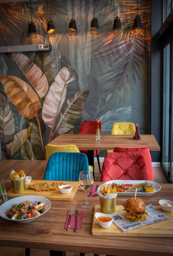Vibrant dining setup with gourmet meals and colorful chairs in an artistic restaurant setting.