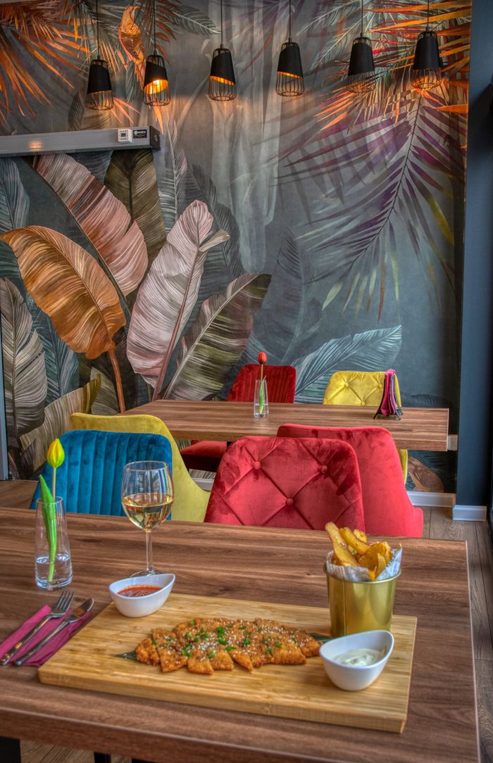Vibrant restaurant interior featuring an artistic wall, wine, and French fries on a wooden table.