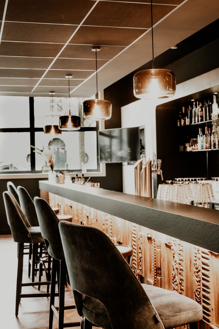 Stylish bar interior with chairs and pendants lights in Valenciennes, France.