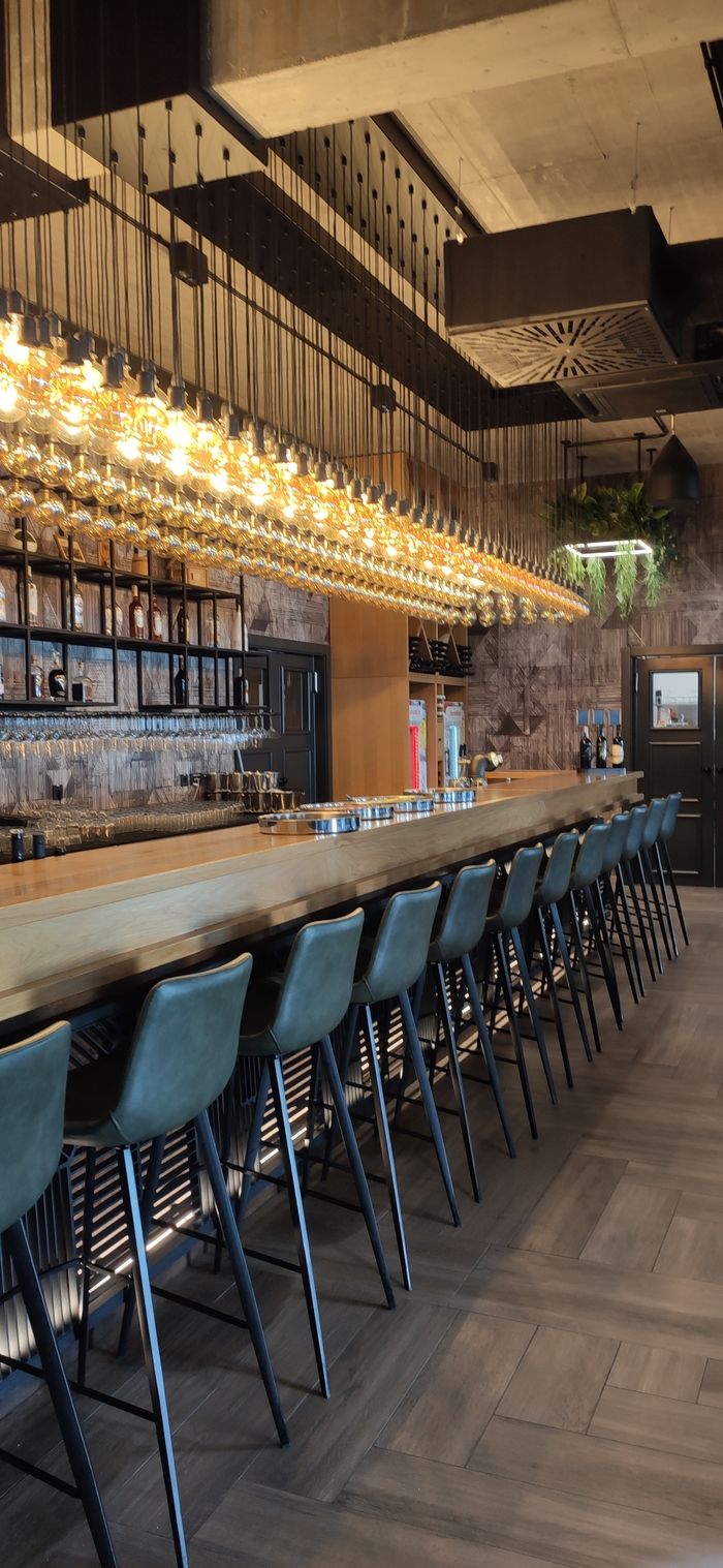 A chic and modern bar interior with elegant lighting and seating arrangement.